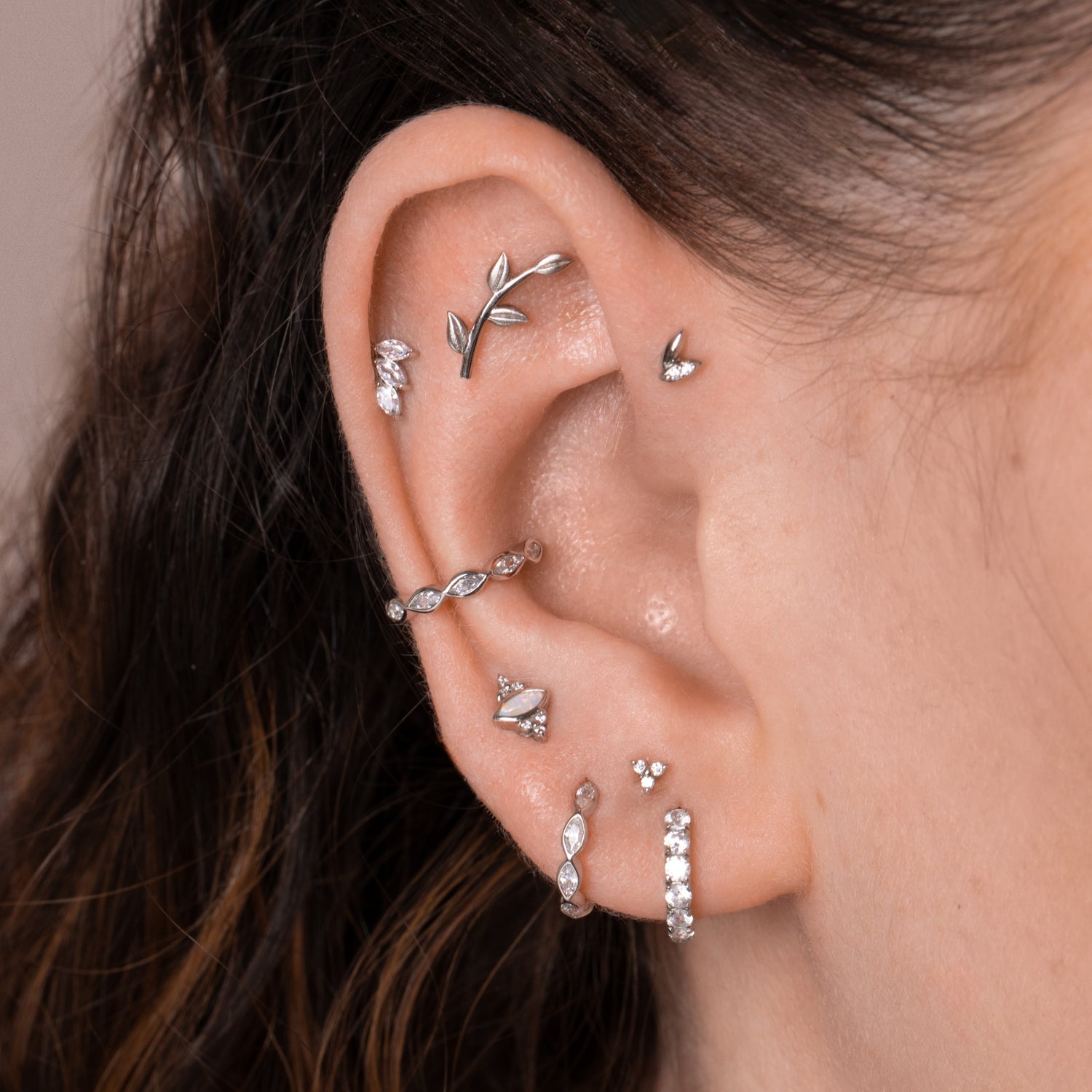 A close-up of an ear stacking arrangement with multiple delicate gold and gemstone earrings.